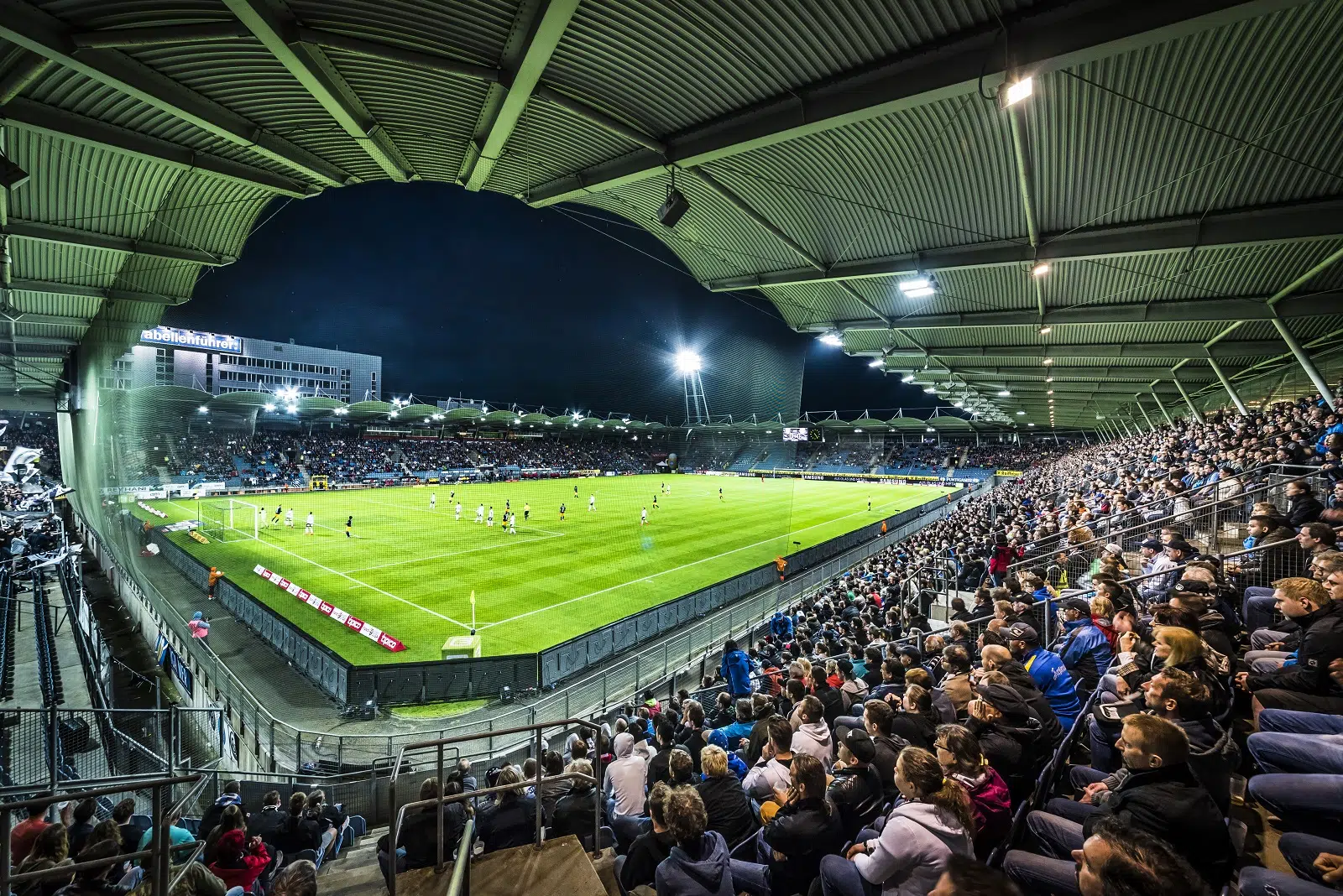 Packed stadium during a night football match with excited fans in the stands